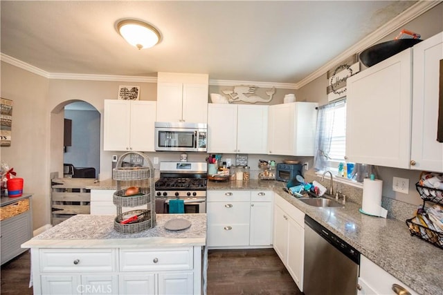 kitchen featuring arched walkways, white cabinets, appliances with stainless steel finishes, ornamental molding, and a sink