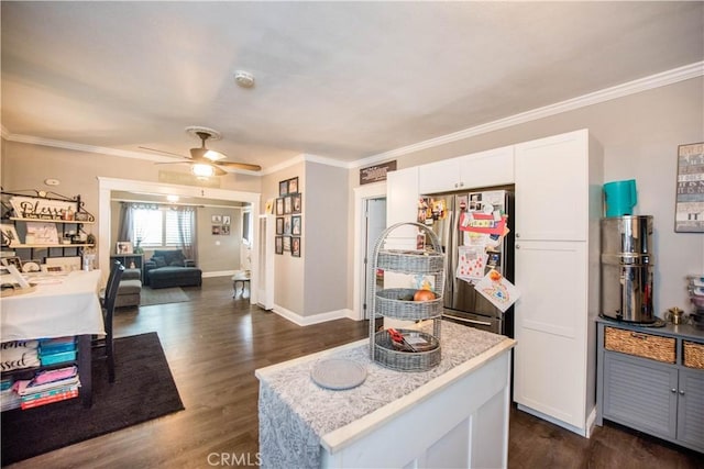 kitchen featuring white cabinets, light countertops, ornamental molding, freestanding refrigerator, and dark wood finished floors