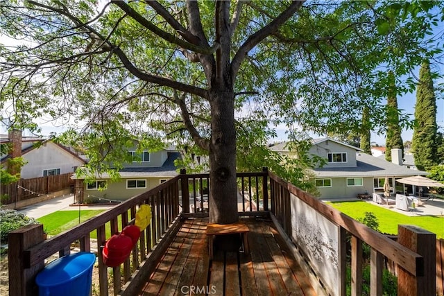 wooden terrace featuring a yard, fence, a patio area, and a residential view