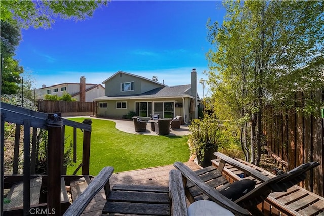 back of house featuring an outdoor living space, a chimney, a lawn, fence private yard, and a wooden deck