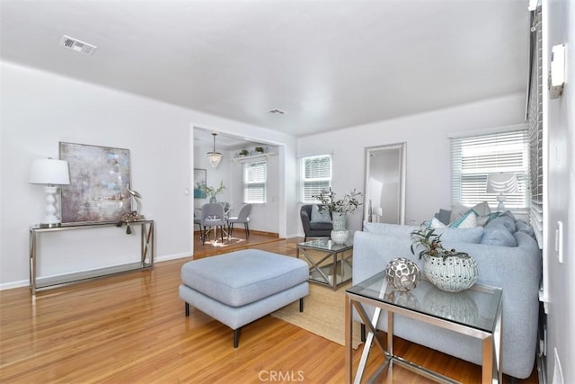 living room featuring baseboards, visible vents, and wood finished floors