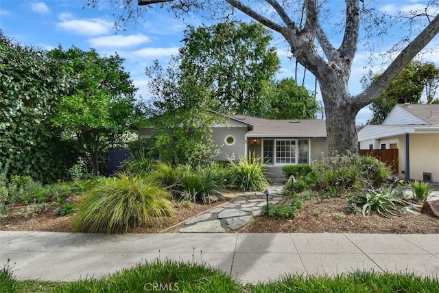 ranch-style house featuring fence and stucco siding