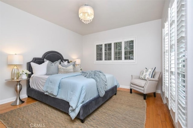 bedroom featuring a notable chandelier, baseboards, and wood finished floors