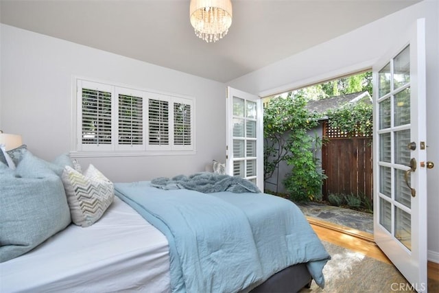 bedroom featuring a chandelier, french doors, and wood finished floors