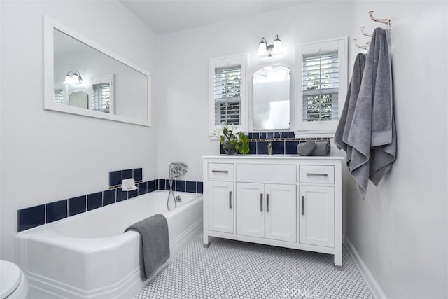 bathroom with baseboards, a bath, and vanity