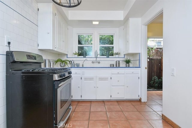 kitchen with light tile patterned floors, tasteful backsplash, white cabinetry, a sink, and gas range