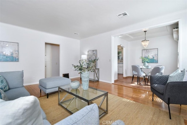 living room with visible vents, baseboards, and wood finished floors