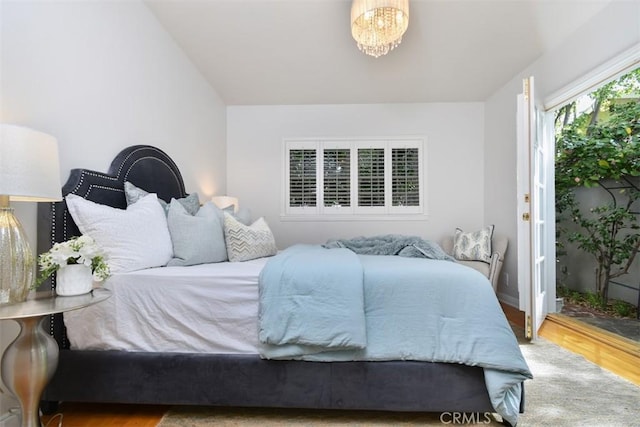 bedroom with lofted ceiling, a notable chandelier, and wood finished floors