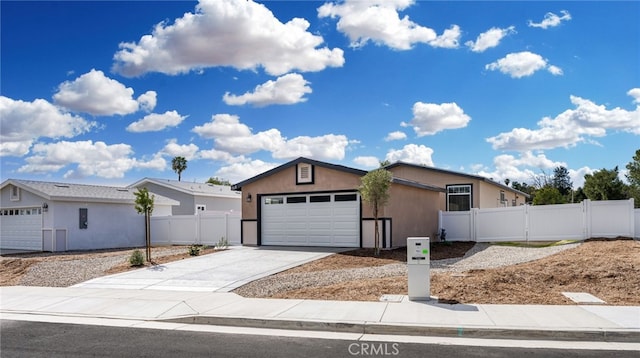 view of front of home with stucco siding, concrete driveway, an attached garage, a gate, and fence