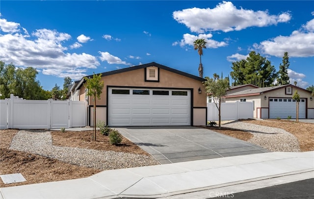 view of front of property featuring stucco siding, concrete driveway, a gate, fence, and a garage