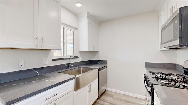 kitchen featuring white cabinets, light wood-type flooring, stainless steel appliances, and a sink