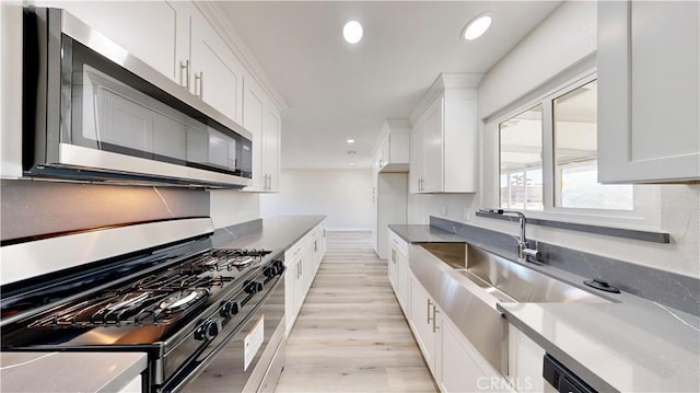 kitchen featuring range with gas stovetop, recessed lighting, stainless steel microwave, and white cabinetry