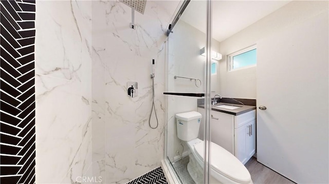 full bath featuring a marble finish shower, vanity, and toilet