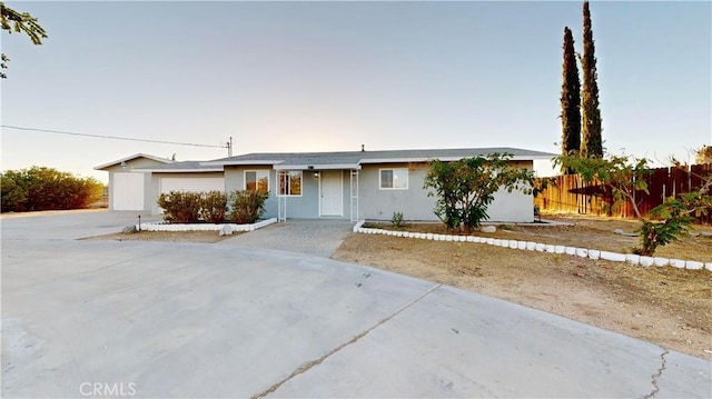 ranch-style house featuring fence and concrete driveway