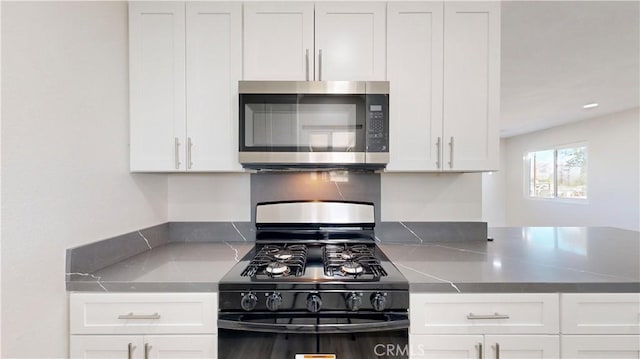 kitchen with stainless steel microwave, white cabinets, and gas stove