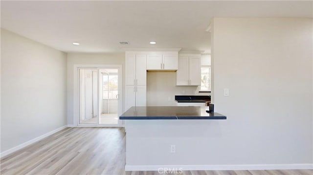 kitchen featuring dark countertops, recessed lighting, light wood-style floors, white cabinetry, and baseboards