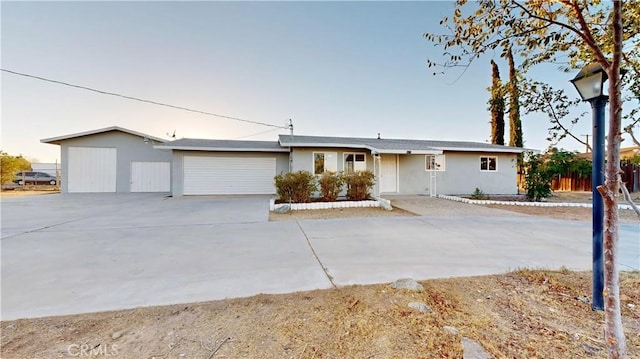 single story home with concrete driveway, fence, and an attached garage