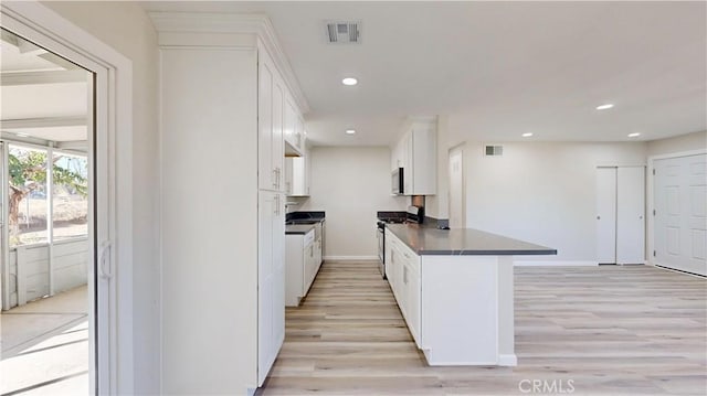 kitchen with dark countertops, gas stove, visible vents, and white cabinets