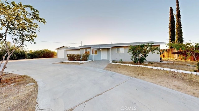 ranch-style home featuring a garage, concrete driveway, and fence