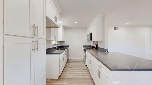 kitchen with stainless steel appliances, a sink, visible vents, white cabinetry, and dark countertops