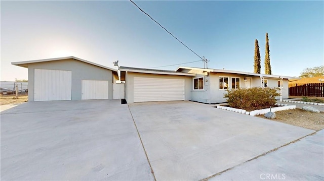 ranch-style house featuring driveway, an attached garage, fence, and stucco siding