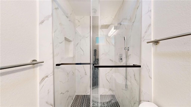 full bath featuring toilet, a marble finish shower, and a textured wall