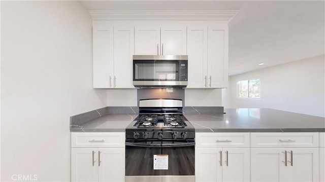 kitchen with a peninsula, stainless steel microwave, black range with gas stovetop, and white cabinetry