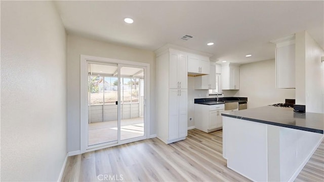 kitchen featuring visible vents, white cabinets, dark countertops, light wood-style flooring, and recessed lighting