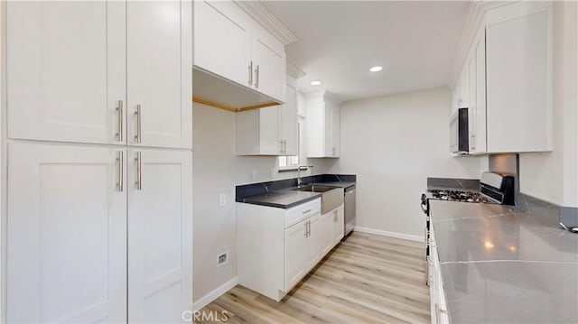 kitchen with white cabinets, light wood-style floors, stainless steel appliances, and a sink