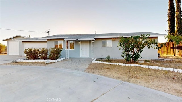 ranch-style house with driveway, an attached garage, fence, and stucco siding