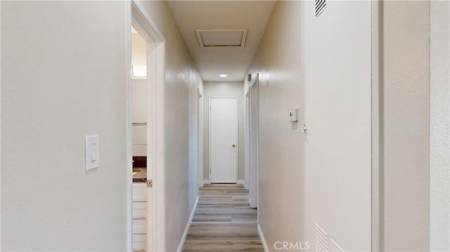 hall featuring attic access, baseboards, and wood finished floors