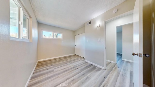 unfurnished room featuring wood finished floors, visible vents, and baseboards