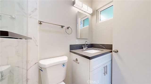 bathroom with walk in shower, vanity, and toilet