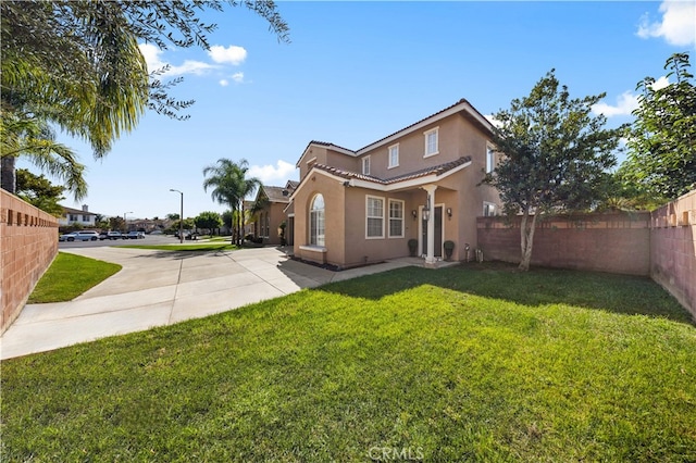 view of front of home with a front lawn, a tile roof, fence, and stucco siding