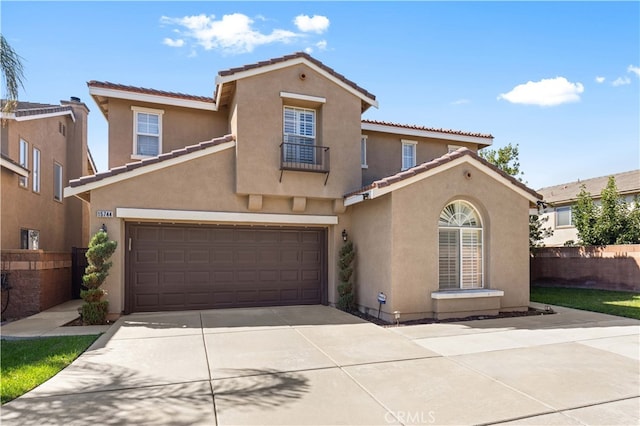 mediterranean / spanish house featuring driveway, a tiled roof, an attached garage, fence, and stucco siding