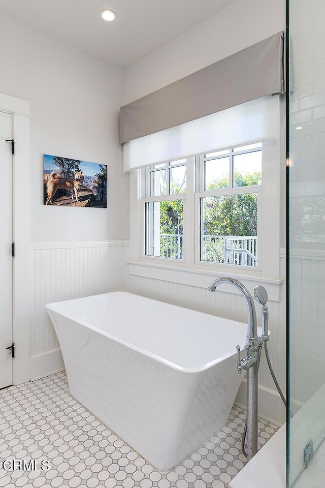 full bathroom featuring recessed lighting, a soaking tub, a wainscoted wall, and tile patterned floors