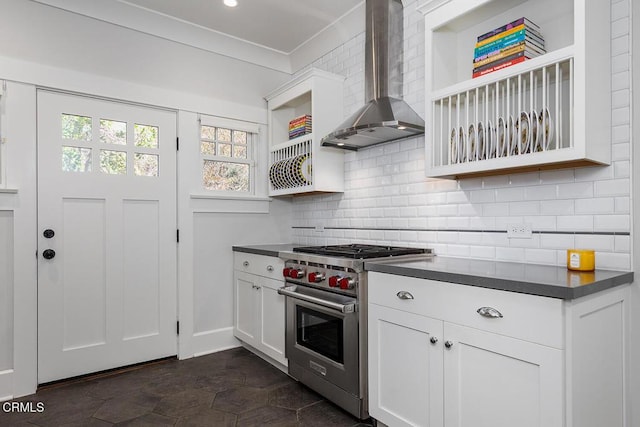 kitchen featuring dark countertops, wall chimney exhaust hood, stainless steel stove, open shelves, and backsplash