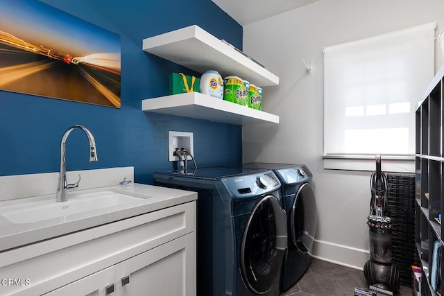 laundry room featuring baseboards, dark tile patterned floors, a sink, and washer and dryer