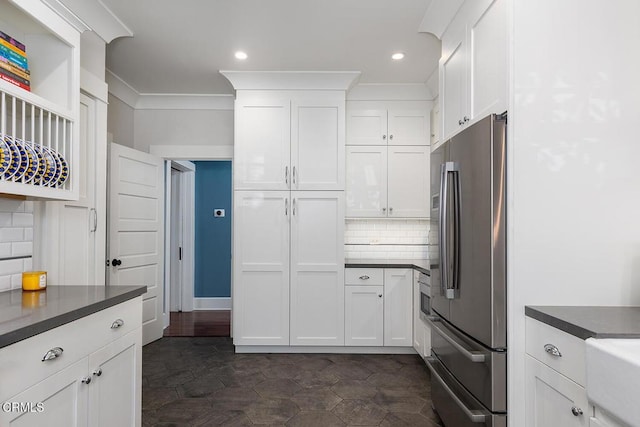 kitchen featuring tasteful backsplash, dark countertops, freestanding refrigerator, and white cabinets