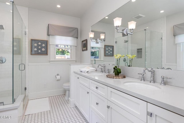 full bathroom featuring a shower stall, visible vents, a sink, and wainscoting