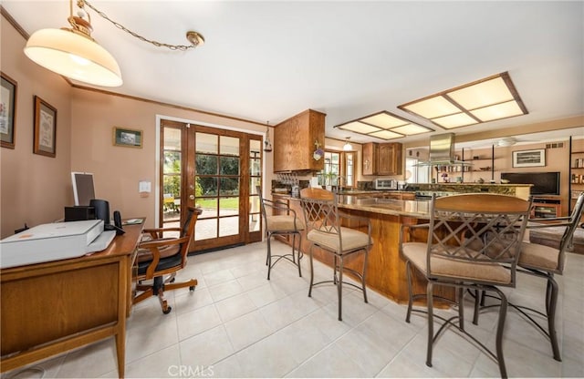 kitchen featuring light tile patterned flooring, island range hood, a peninsula, french doors, and brown cabinets