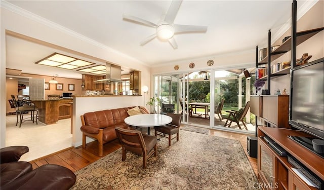 living room with ornamental molding, light wood-style flooring, and a ceiling fan