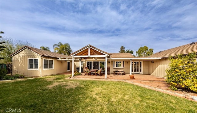 back of property with a patio area and a lawn