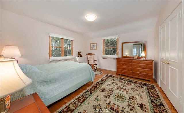 bedroom with light wood-style floors, multiple windows, and baseboards