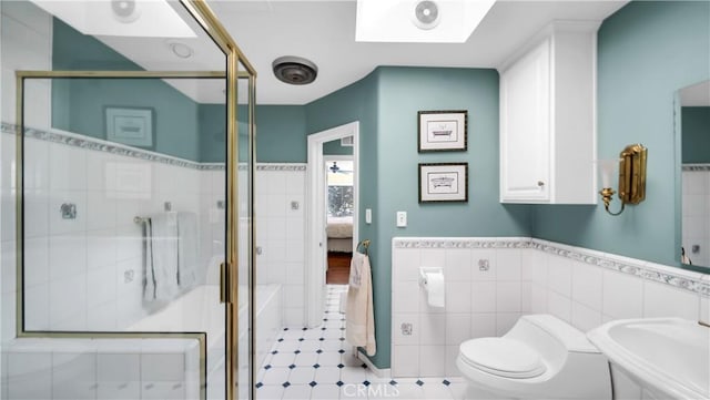 full bath featuring a wainscoted wall, tile walls, toilet, a sink, and a shower stall