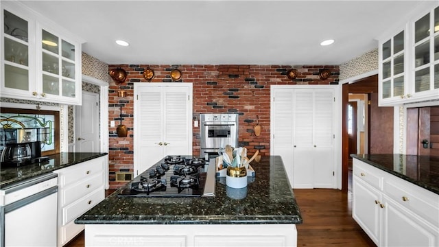 kitchen with black gas cooktop, brick wall, glass insert cabinets, and white cabinets