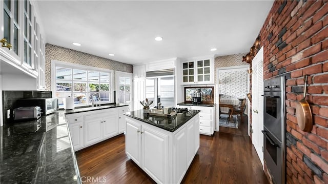 kitchen with stainless steel appliances, dark wood finished floors, white cabinets, and a sink