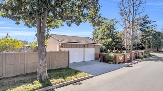 view of property exterior featuring a garage, driveway, fence, and a tiled roof