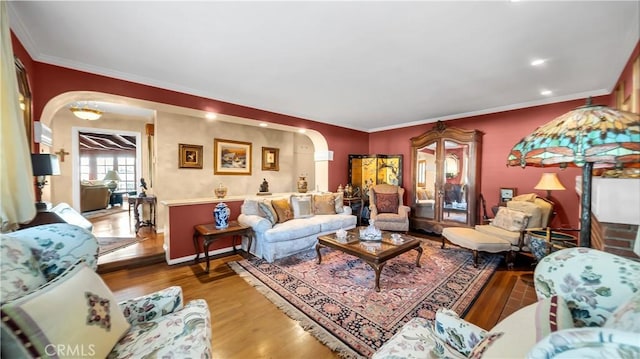 living room featuring baseboards, arched walkways, wood finished floors, and ornamental molding