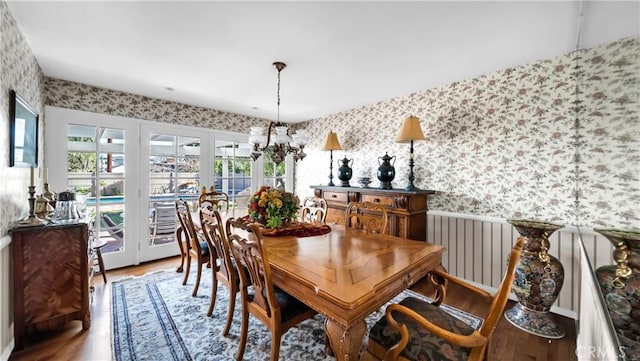 dining room featuring wallpapered walls, a chandelier, and wood finished floors